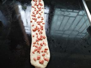面团擀开，不用太宽，长45cm，铺上香肠粒