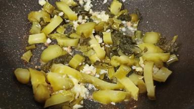 锅里加少许的油，爆香生姜蒜泥辣椒段，我加酸菜翻炒出香味。