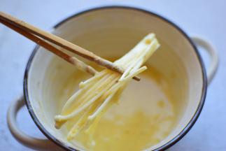 把金针菇蘸满鸡蛋面粉糊，一定要裹满哦，炸出来的蘑菇口感才够好，如果不愿意像我这么一点一点的裹面糊，可以把金针菇一次性全部倒面糊中，拌匀就行了