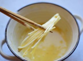 把金针菇蘸满鸡蛋面粉糊，一定要裹满哦，炸出来的蘑菇口感才够好，如果不愿意像我这么一点一点的裹面糊，可以把金针菇一次性全部倒面糊中，拌匀就行了