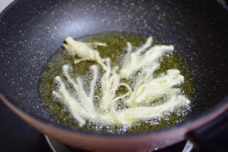 锅中加足够的油，油热后，把金针菇夹进锅中，保持中火炸即可