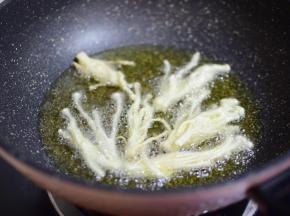 锅中加足够的油，油热后，把金针菇夹进锅中，保持中火炸即可