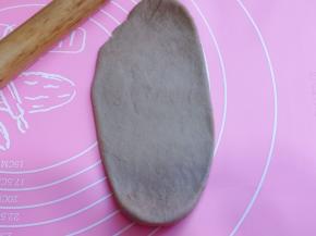 取一块面团，用擀面杖擀长舌状。