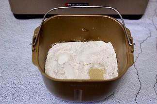 面包机里加入奶粉，全蛋液、花生油，加入高筋面粉和低筋面粉，让面粉覆盖整个上面，在面粉的顶端两边各挖个小洞，加入酵母粉和盐，再用面粉把酵母粉盖起来。