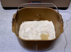 面包机里加入奶粉，全蛋液、花生油，加入高筋面粉和低筋面粉，让面粉覆盖整个上面，在面粉的顶端两边各挖个小洞，加入酵母粉和盐，再用面粉把酵母粉盖起来。