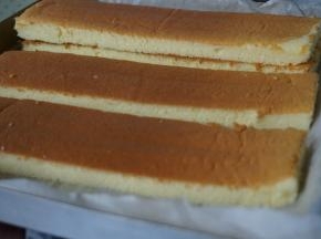 烘烤结束，将蛋糕取出，晾3分钟倒扣在另一张干净的油纸上，趁热撕掉底部的油纸，待蛋糕放凉后，切掉四条边，再切成4等份