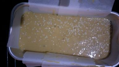 将蛋糕糊倒入模具中，震几下震出气泡，表面撒适量白芝麻装饰