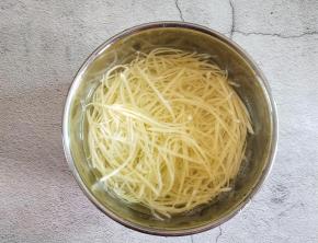 把土豆擦丝放入清水中浸泡，防止它氧化。接下来白醋就要出场了！在水里面加一勺白醋，浸泡五分钟，第一勺醋，把土豆丝面的淀粉去除干净，这样土豆丝在炒熟之后就不会出现黏黏的，粉粉的感觉。