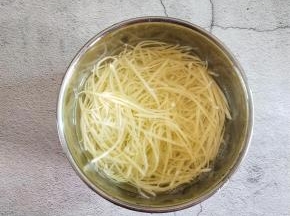 把土豆擦丝放入清水中浸泡，防止它氧化。接下来白醋就要出场了！在水里面加一勺白醋，浸泡五分钟，第一勺醋，把土豆丝面的淀粉去除干净，这样土豆丝在炒熟之后就不会出现黏黏的，粉粉的感觉。