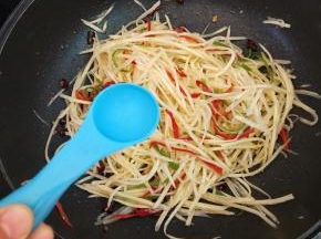 然后放一勺醋翻炒均匀。第二勺醋的主要作用就是润锅，防止土豆丝烧糊粘锅，同时让土豆丝酸得更有内涵