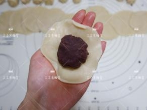 取30克豆沙馅包入，捏紧收口压扁