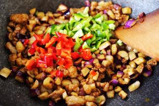 看见茄子断生变软的时候，加入青红辣椒丁。