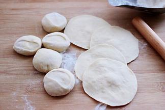 然后把面团摁扁后，用擀面杖擀成圆形薄面皮。