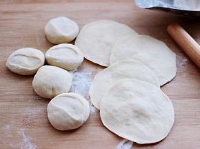 然后把面团摁扁后，用擀面杖擀成圆形薄面皮。