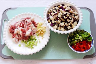 把猪肉，茄子、青红辣椒洗净后全部用刀切成小丁，葱姜切碎备用。