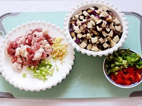 把猪肉，茄子、青红辣椒洗净后全部用刀切成小丁，葱姜切碎备用。