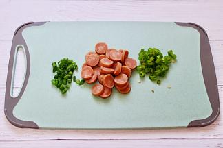 把火腿肠去皮后用刀切成薄片，青椒和小香葱切成碎末。