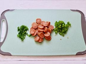 把火腿肠去皮后用刀切成薄片，青椒和小香葱切成碎末。