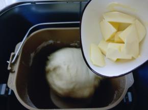 揉面20分钟后，加入提前室温软化的黄油。继续启动面包机揉面15分钟，这时面团已经有手套膜。