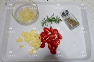 大蒜切成碎末与30克橄榄油混合拌匀，土豆切成小片，小番茄对半切开