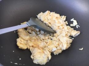当葱姜油温度达到5、6成热时，放入鸡蛋液，待蛋液稍稍凝固后，用铲子将鸡蛋铲碎。