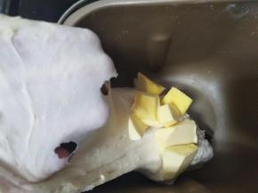 先把牛奶、蛋液、酵母、糖'、奶粉和高筋面粉倒入面包桶，启动一个揉面程序，加入黄油