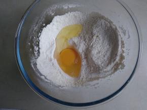 面粉、泡打粉混合倒入和面盆里，磕入一个鸡蛋