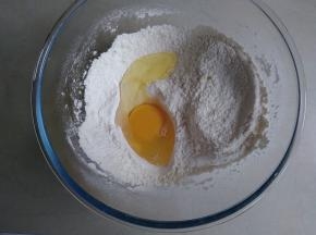 面粉、泡打粉混合倒入和面盆里，磕入一个鸡蛋