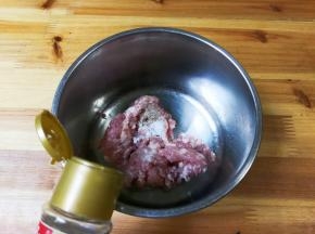 盆中放入肉糜，放入一小勺盐，放入少许白胡椒粉，搅拌至有粘性