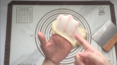 再次开启面包机的揉面功能，揉到面团呈扩展性能拉出厚膜来，面团的膜是坚韧的就可以了，因为做的是餐包不需要揉出手套膜来