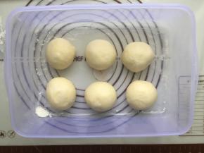 发好的面团拿到揉面垫上，进行简单的按压排气，然后平均分成6个等份，分别揉圆，盖上保鲜膜，进行室温醒发15分钟