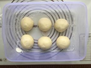 发好的面团拿到揉面垫上，进行简单的按压排气，然后平均分成6个等份，分别揉圆，盖上保鲜膜，进行室温醒发15分钟