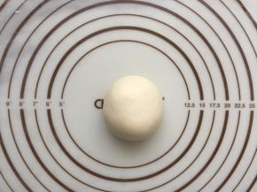 醒发好的面团再次拿出来排气，用擀面杖先擀成平，再收捏起来整型成圆形的