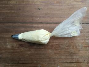 裱花嘴提前放入裱花袋，将裱花袋剪开至裱花嘴一半的位置，然后将拌好的面糊装入裱花袋