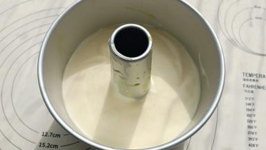 倒入全部的牛奶糊，震一下模具。然后再用刮刀刮齐边缘。