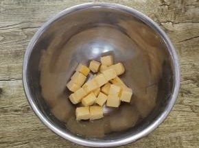 我们先把黄油切成小块放入碗中，自然软化