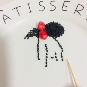 用牙签把熟黑芝麻摆成少女的背影，再用两颗石榴摆在头发上，就成了一个漂亮的蝴蝶结啦！