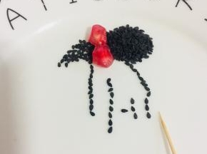 用牙签把熟黑芝麻摆成少女的背影，再用两颗石榴摆在头发上，就成了一个漂亮的蝴蝶结啦！