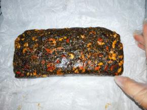 戴手套操作，把阿胶糕移至油纸上面，先用刮刀压到一团，然后用油纸包住阿胶糕，压实整形。