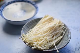 金针菇切掉根部，洗净后，掰成小朵备用；粉丝洗净后，用温水浸泡15分钟