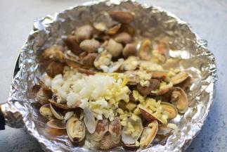 锅中垫一张锡纸，把煮好的花甲、姜、蒜，放在进去