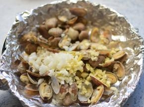 锅中垫一张锡纸，把煮好的花甲、姜、蒜，放在进去