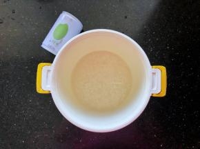9、九阳鲜米用清水洗净后倒入焖饭煲中，倒入一罐清水。