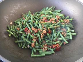 放入豇豆及50g左右的水，翻炒均匀，大火烧开，转小火焖至熟透。
如果是极火烧制虚适当的多放些水。
豇豆需加热10分钟以上，以保证豇豆熟透，有害物质就会分解变成无毒物质了。
但是也要根据豇豆的质地，质地较嫩的豇豆适当缩短烧制时间。