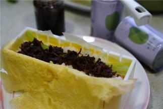 在寿司模里加放上蛋皮，码上米饭再加入胡萝卜芹菜及牛肉酱