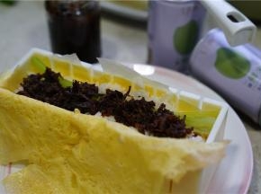 在寿司模里加放上蛋皮，码上米饭再加入胡萝卜芹菜及牛肉酱