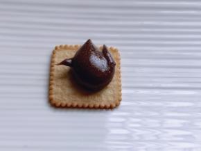 取一块饼干，放上可可牛轧糖！上面再放一块饼干，轻轻按压即可！