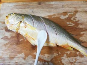 黄鱼刮去鱼鳞去掉鱼肠鱼鳃洗净，在表面划切数刀，黄鱼里外都撒上一小勺盐，用手摩擦几下，腌制半小时