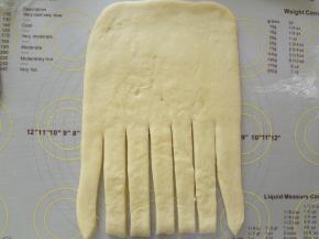 松弛好的面团擀成长方形，翻面底部切开几条，(切口光滑不粘连烤出来才好看）