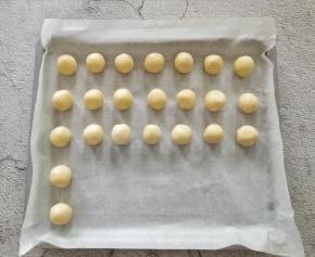 取一个小面团，搓圆，放在垫有油纸的烤盘里，中间要留一些空隙